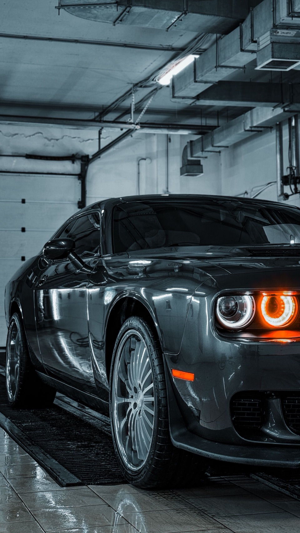 Black muscle car with corrected, glossy paint in a detailing bay