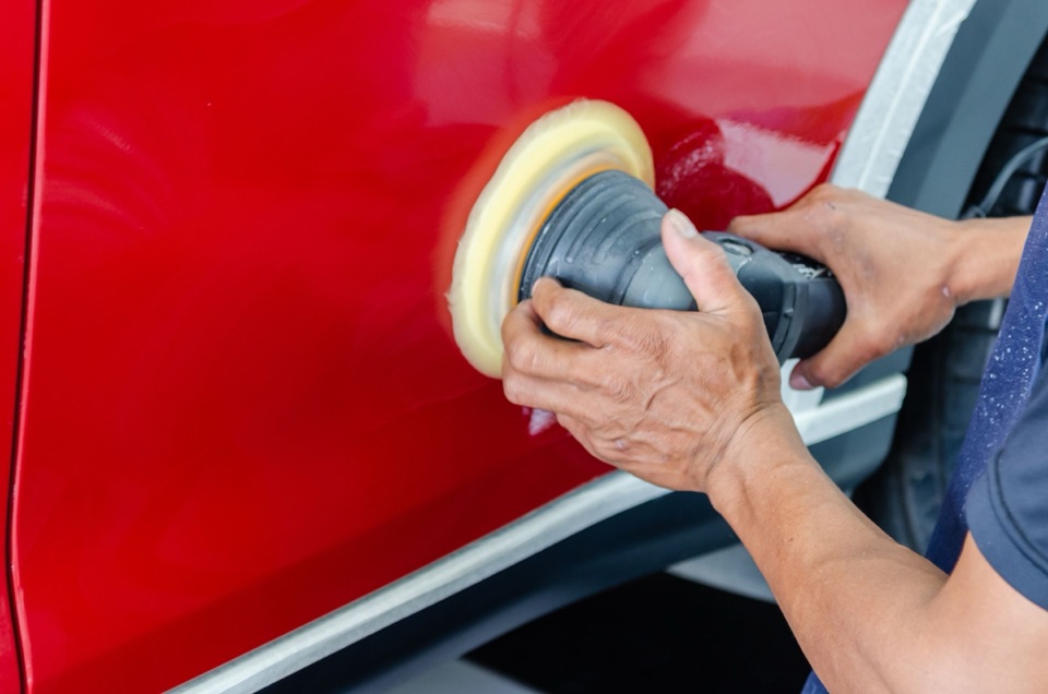 Machine polisher correcting the paint on a red door